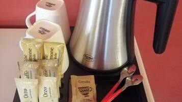 A coffee maker, two white cups, and several packets of Orzo and Consilia on a tray.