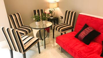 Un salon moderne avec des fauteuils à rayures, un canapé rouge et une table ronde en verre.