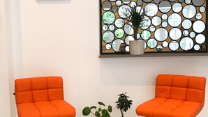 Two orange chairs with wooden legs and a black table with potted plants between them. - The Hurdwick (London)