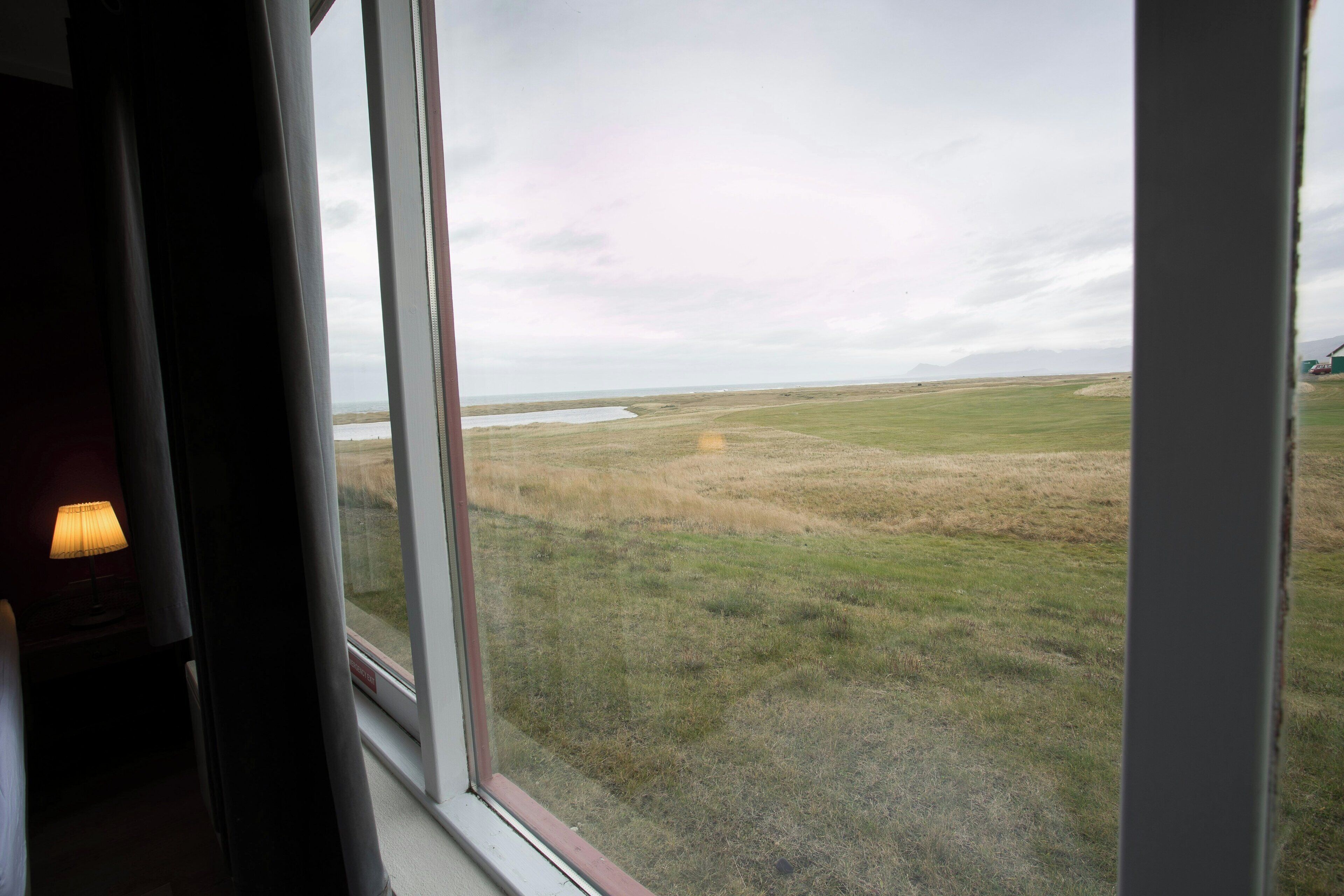 Ein Zimmer mit großem Fenster und Blick auf eine grüne Wiese.