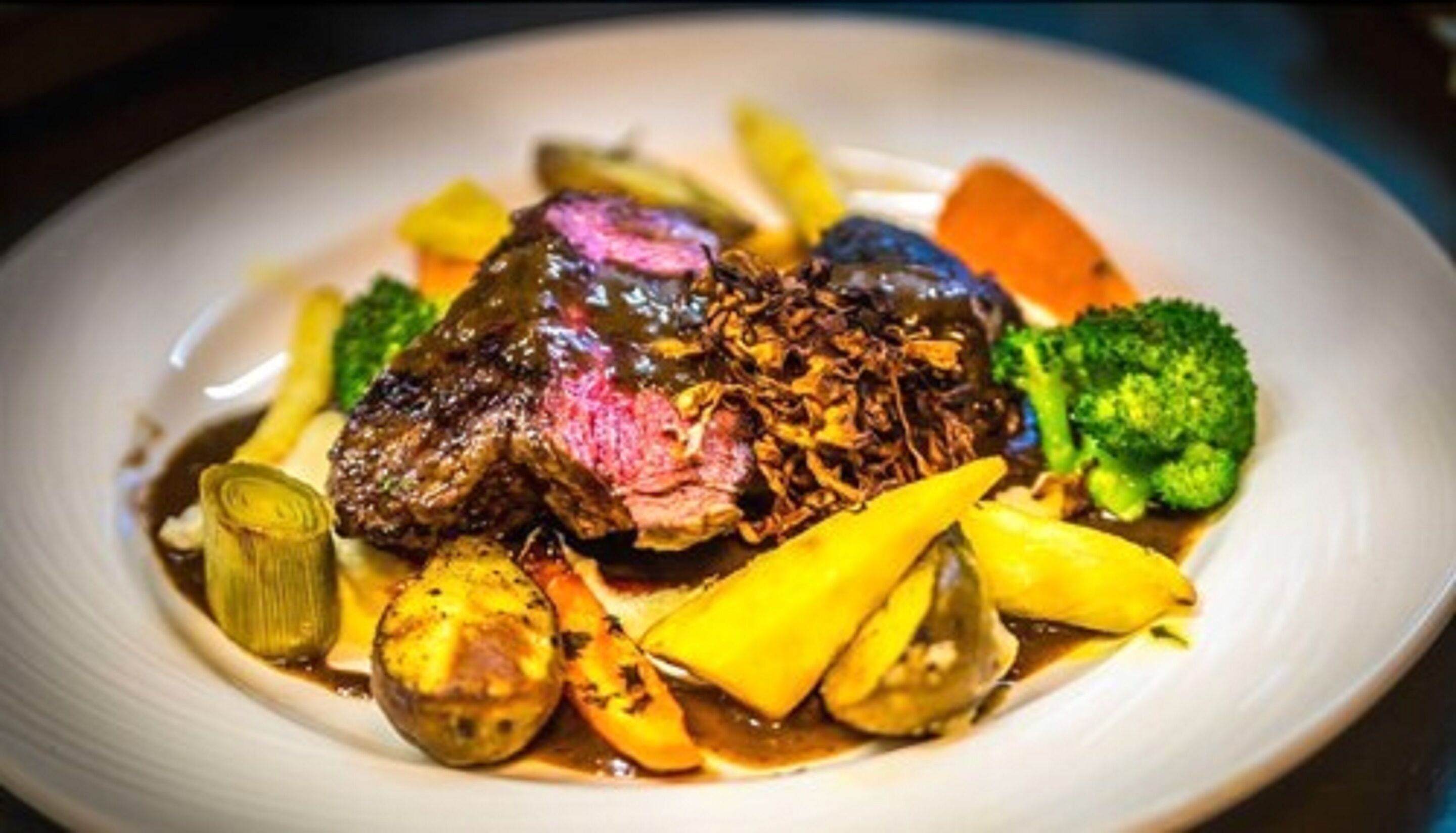A plate of food with a steak, vegetables, and sauce.