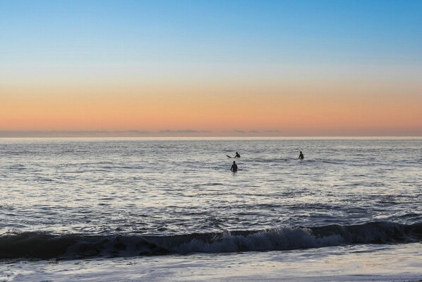 Una playa con olas y un atardecer.