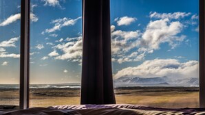 Une pièce dotée d’une grande fenêtre donnant sur une plage et des montagnes.