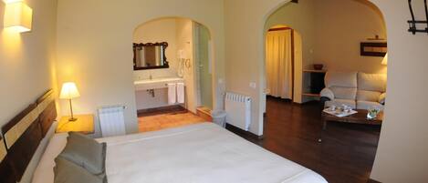 Un dormitorio con una cama grande, un baño y una sala de estar con sofá y mesa.