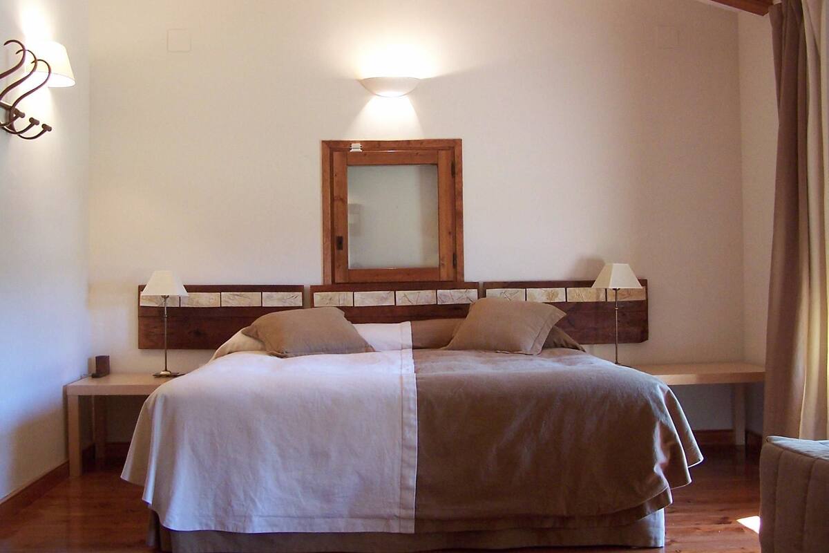 A bedroom with a large bed, wooden headboard, bedside lamps, and a mirror.