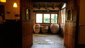 A reception area with wooden doors, stone flooring, and large vases. - Hotel Rural Font del Pas (Beceite)