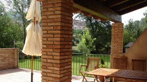 A covered patio area with a brick pillar, a table, and chairs. - Hotel Rural Font del Pas (Beceite)