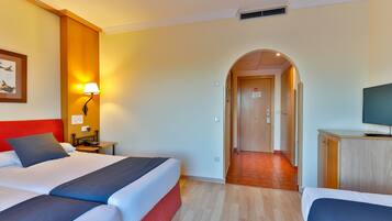 Une chambre d’hôtel avec deux lits, un bureau, une lampe et un téléviseur.