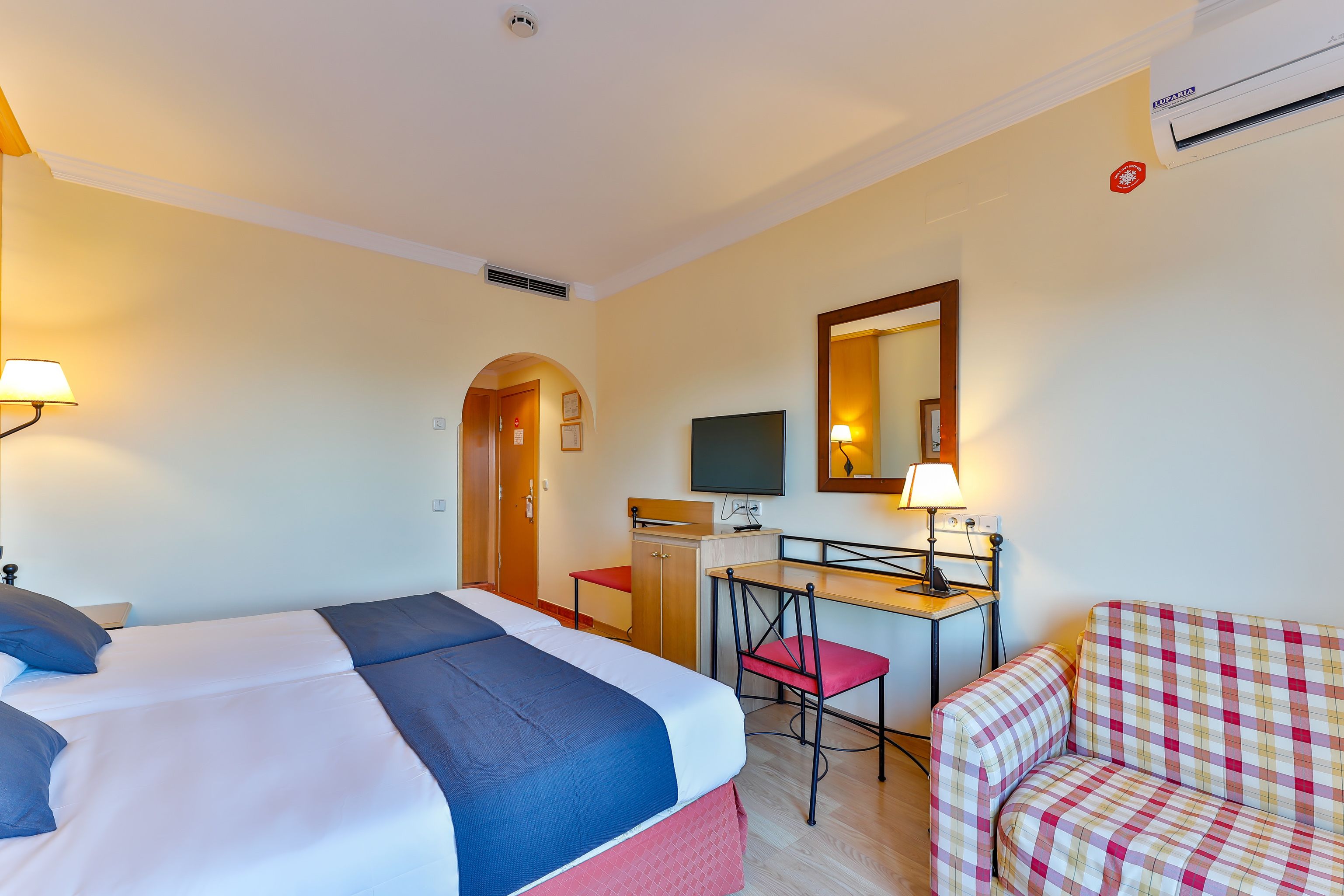 A hotel room with a bed, desk, chair, and a television.