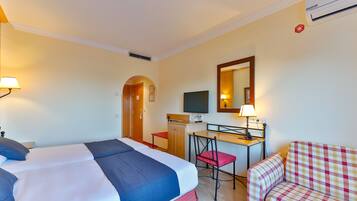 A hotel room with a bed, desk, chair, and a television.