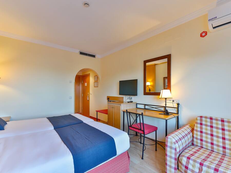 A hotel room with a bed, desk, chair, and a television.