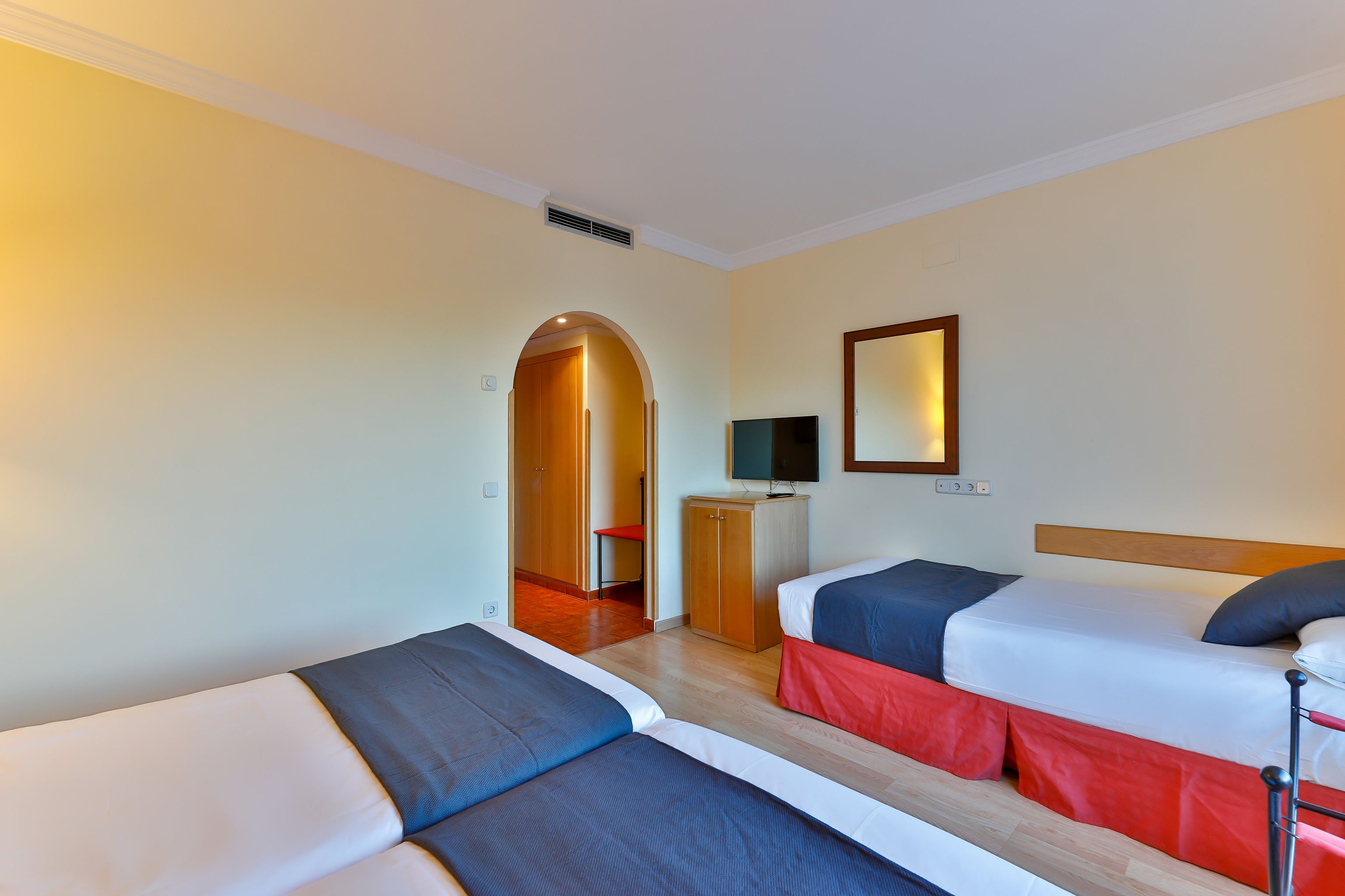 Une chambre d’hôtel avec deux lits, une télévision et une armoire en bois.