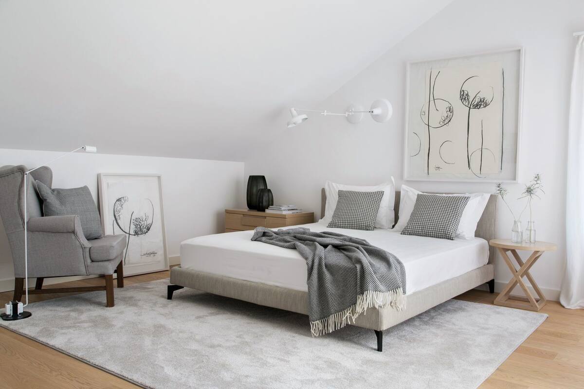 Ein Schlafzimmer mit Bett, Stuhl, Nachttisch, Lampe und Wandbildern.