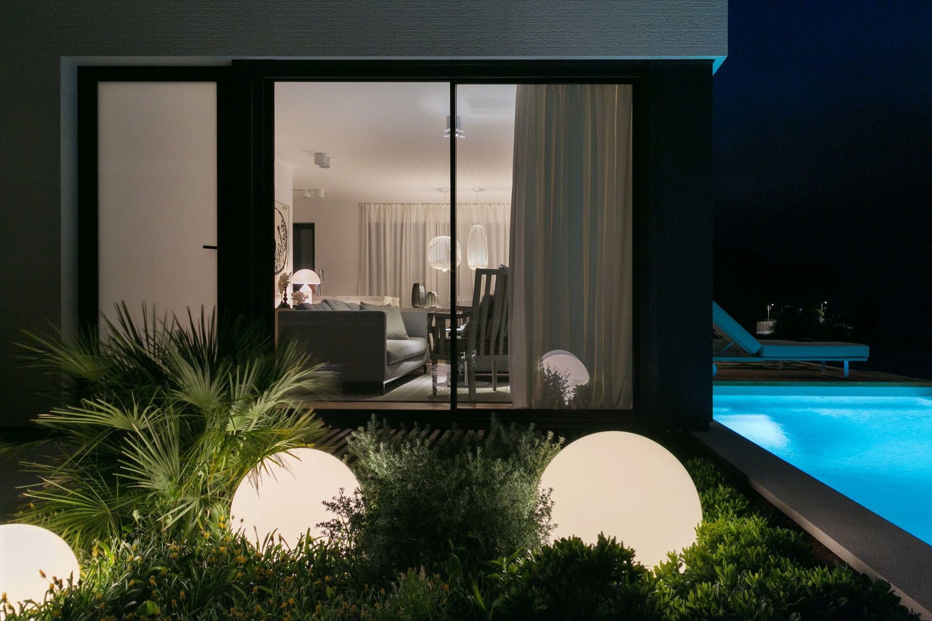 Ein modernes Haus mit Pool, Essbereich und Wohnzimmer mit Sofa und Tisch.