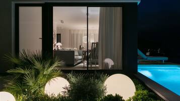 Una casa moderna con piscina, comedor y sala de estar con sofá y mesa.