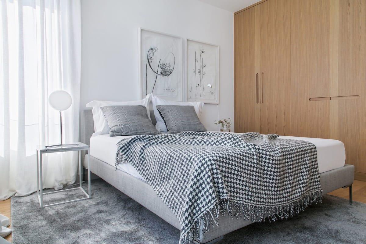 Ein Schlafzimmer mit Bett, Nachttisch, Lampe und Kleiderschrank.