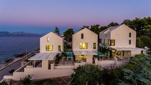 A modern coastal property with three white buildings, a swimming pool, and a view of the sea. - Omega Villas Complex (Sutivan)