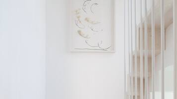 A staircase with a minimalist design, leading to a landing with a framed artwork.