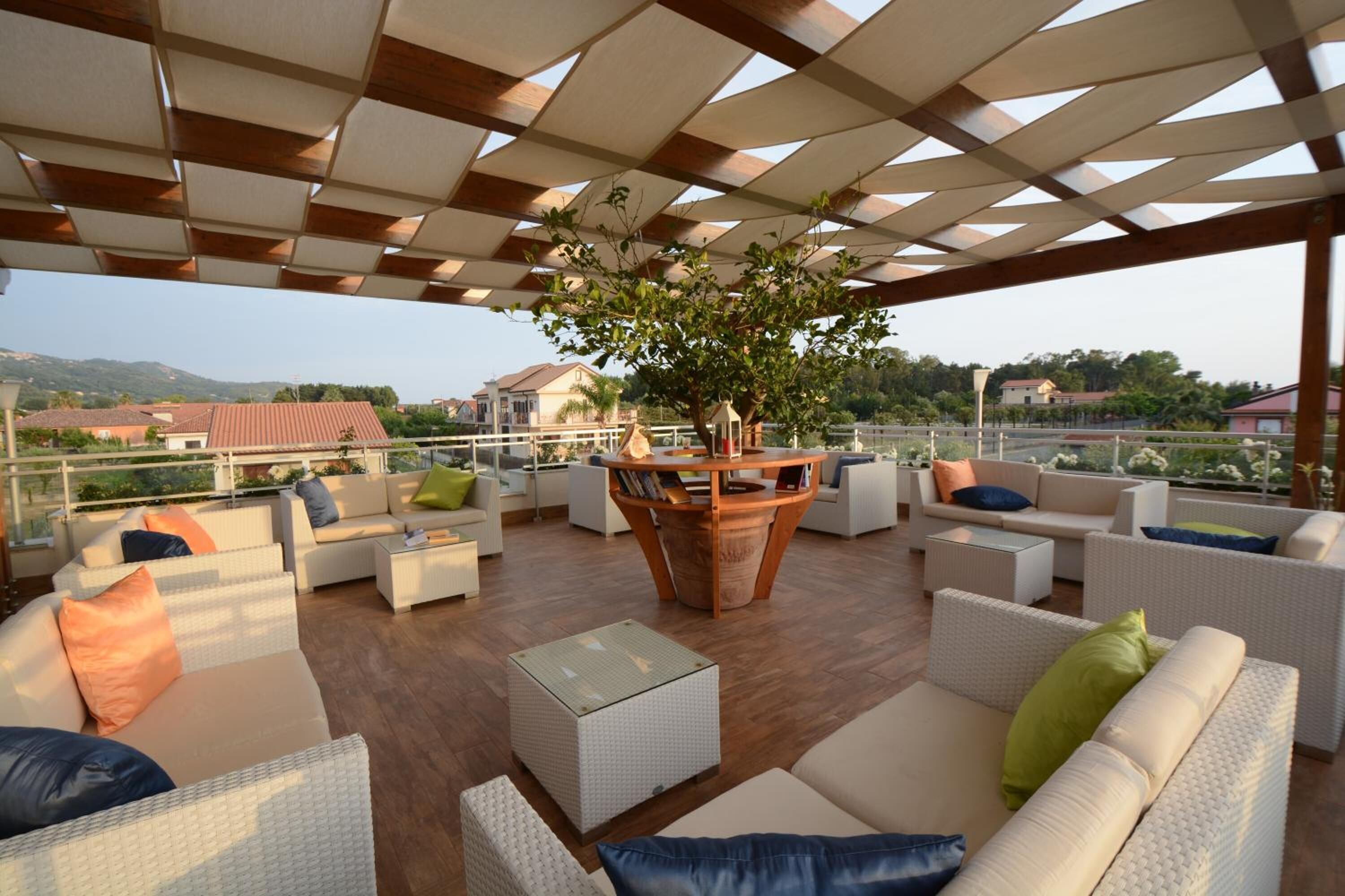 An outdoor seating area with wicker furniture, a central wooden table, and a view of the surrounding landscape.