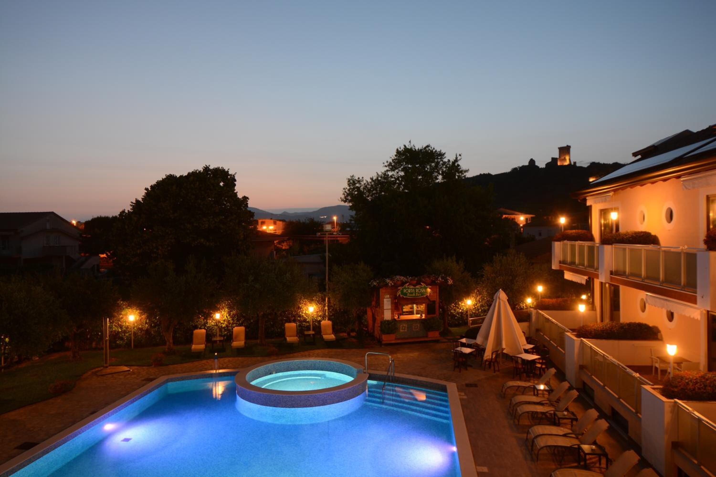 Una piscina con idromassaggio, circondata da sdraio e un ristorante.