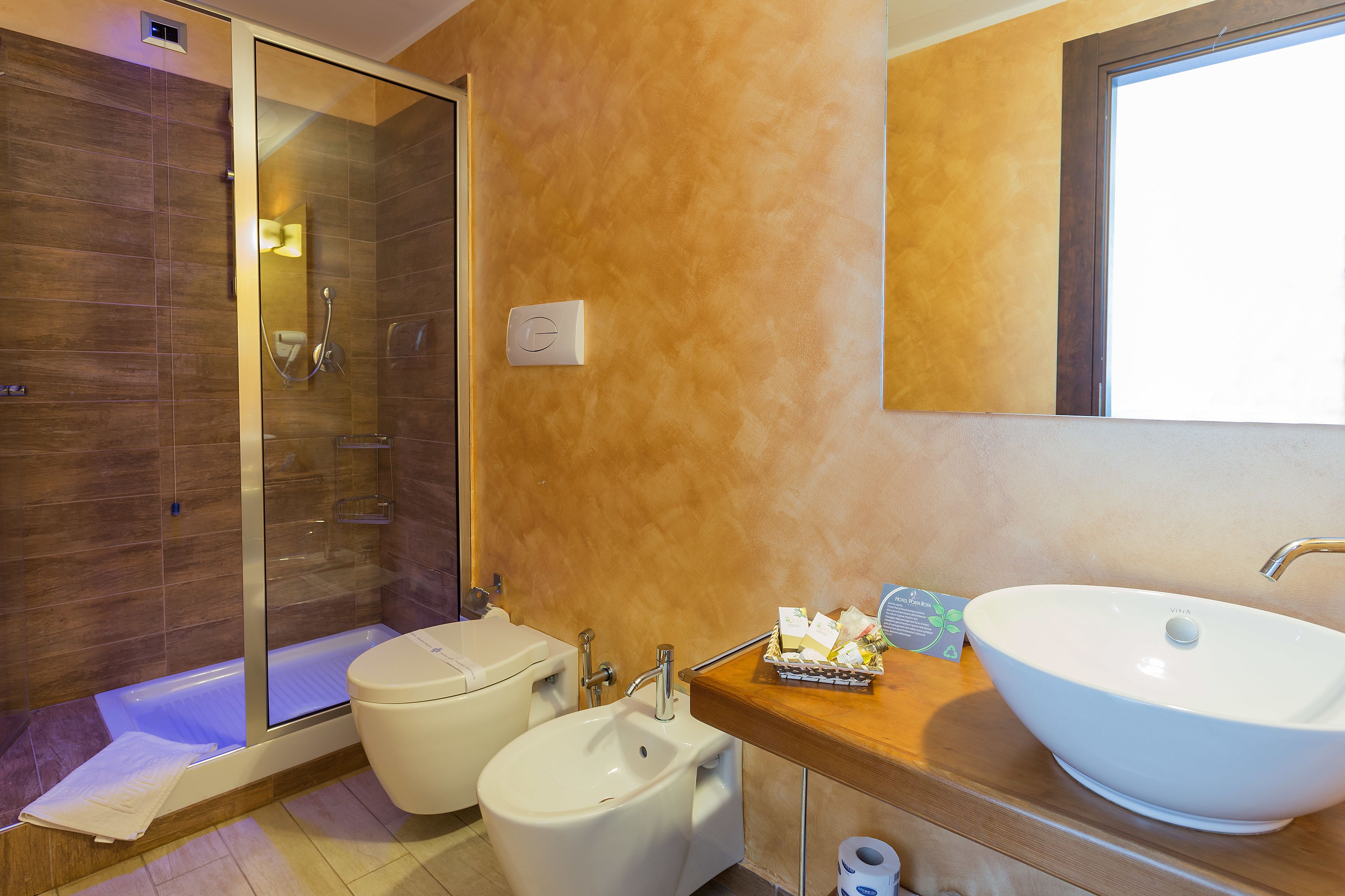 A modern bathroom with a glass-enclosed shower, a bidet, and a large vessel sink.