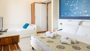 A hotel room with a bed, a sofa, a desk, and a large wall mural. - Hotel Porta Rosa (Ascea)