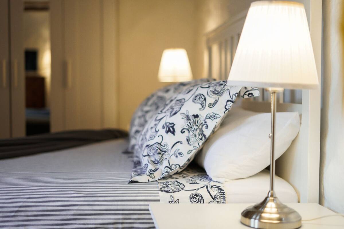 Ein Hotelzimmer mit Bett, Nachttischlampe und einem gemusterten Überwurf.