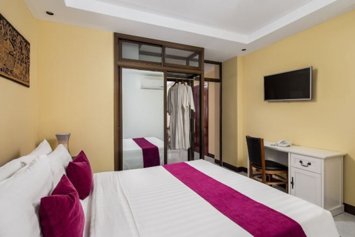 Une chambre d’hôtel équipée d’un lit, d’un bureau, d’une chaise, d’une télévision et d’une porte coulissante donnant accès à la salle de bain.