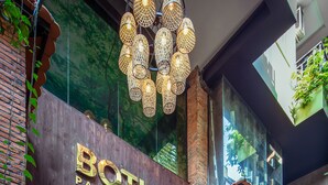 The exterior of Botum Hotel with a modern design, featuring a prominent entrance, large potted plants, and a unique hanging light fixture. - Botum Palace Hotel (Phnom Penh)