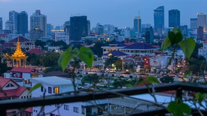 A cityscape with a prominent golden pagoda, modern buildings, and a mix of residential and commercial structures. - Botum Palace Hotel (Phnom Penh)