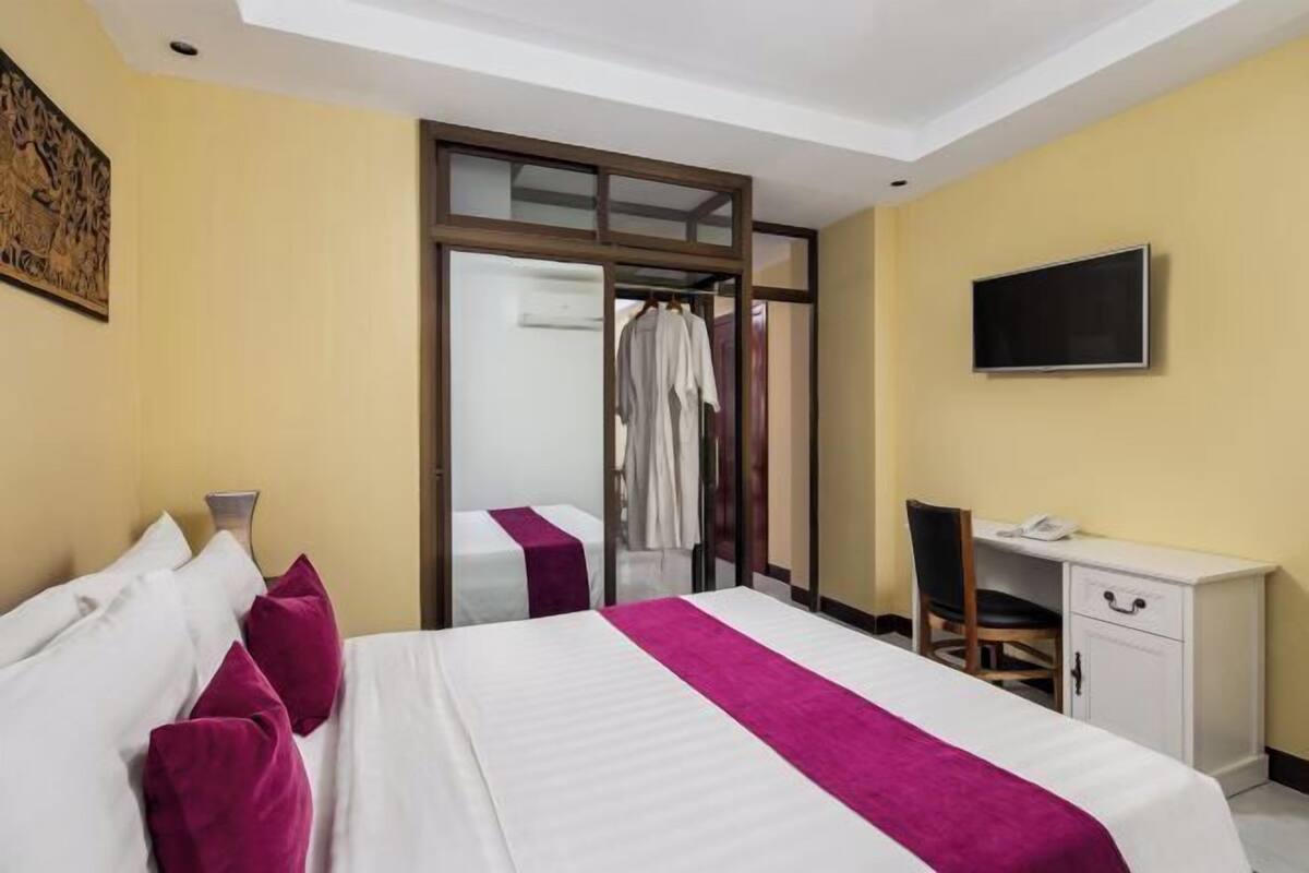 A hotel room with a bed, a desk, a TV, and a wardrobe.