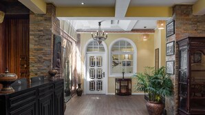 A reception area with a wooden reception desk, a large potted plant, and a chandelier. - Botum Palace Hotel (Phnom Penh)