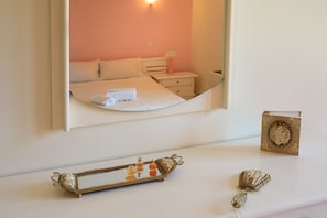 A bedroom with a bed, bedside tables, a mirror, and decorative items.