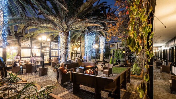 Eine Außenpatio-Terrasse mit Sitzgelegenheiten, einem Feuerkorb und dekorativer Beleuchtung.
