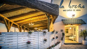 A hotel entrance with a wooden overhang, potted plants, and a sign reading "la breta los caños de meca". - Hotel Gastronómico La Breña (Barbate)
