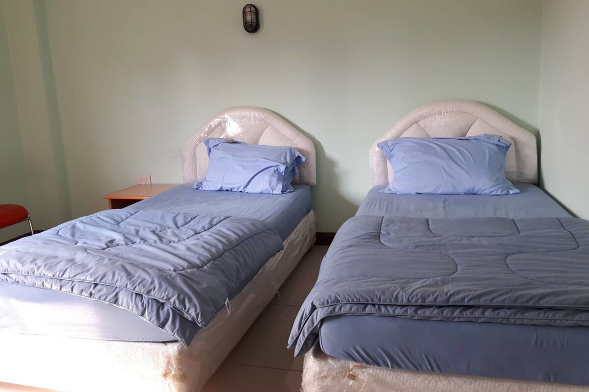 Two single beds with headboards, a small wooden nightstand, and a red chair.