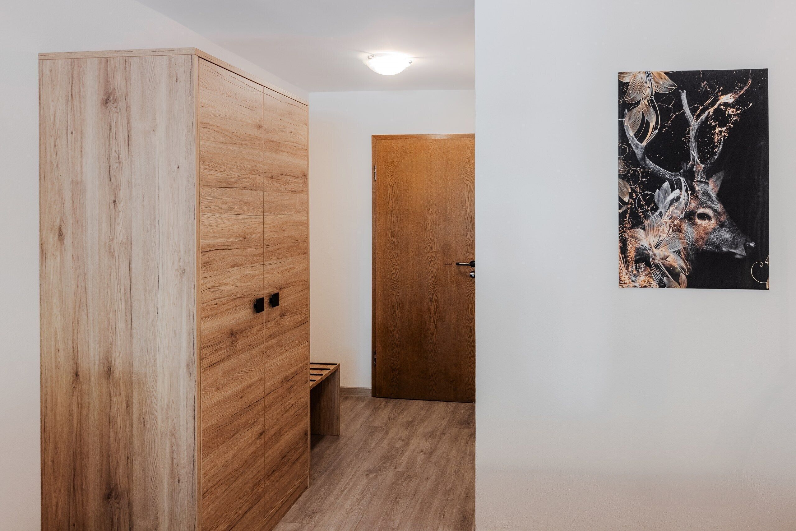 A hallway with a wooden wardrobe, a bench, and a door.