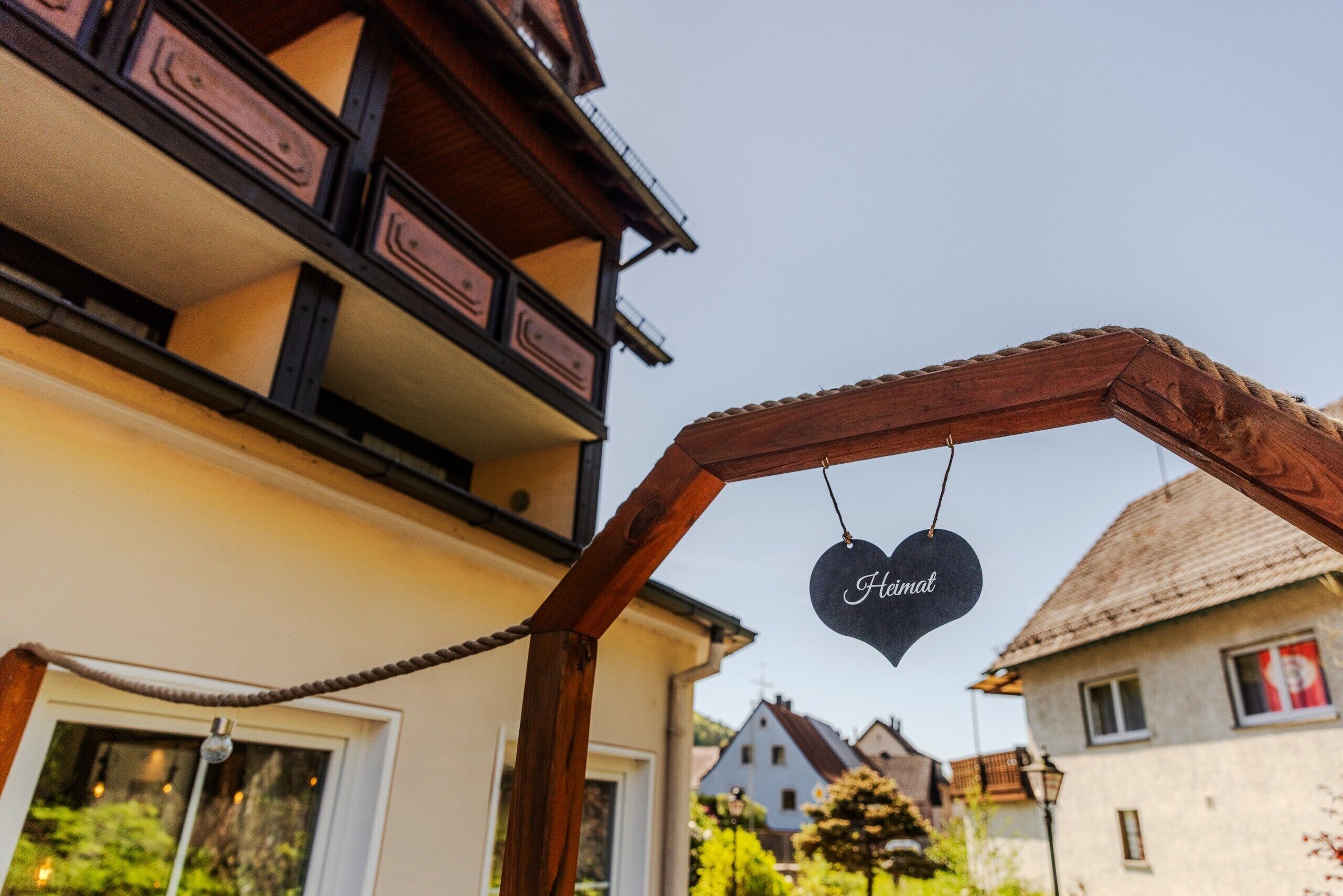 A traditional wooden balcony with a heart-shaped sign hanging from the railing.