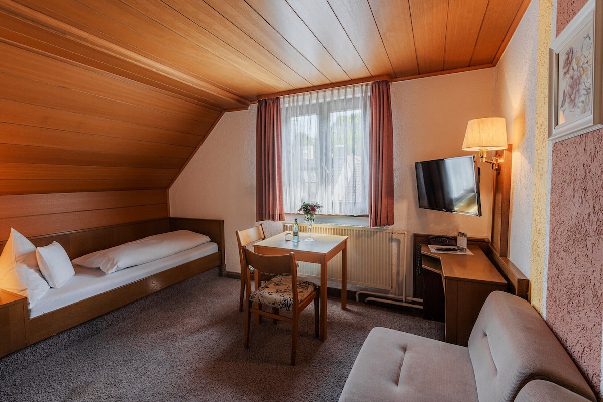 Une pièce confortable avec un lit, une petite table et une chaise, un bureau avec une lampe et un téléviseur.