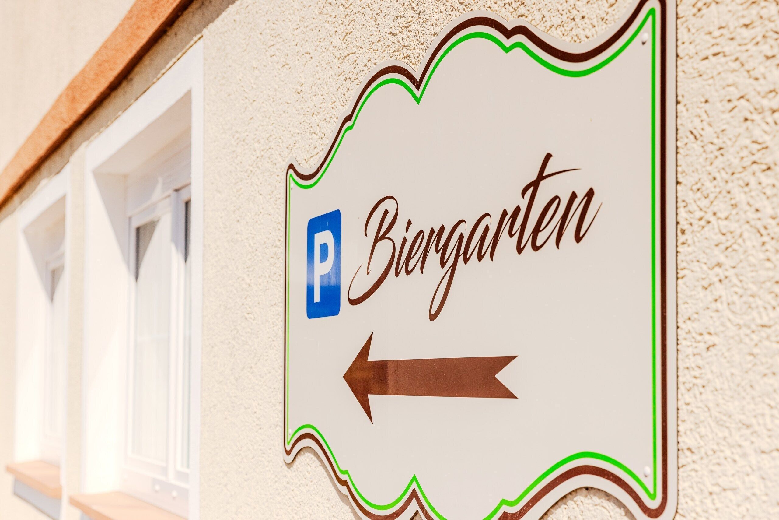 Un letrero con la palabra 'Biergarten' y una flecha apuntando a la izquierda, indicando el camino hacia el Biergarten.