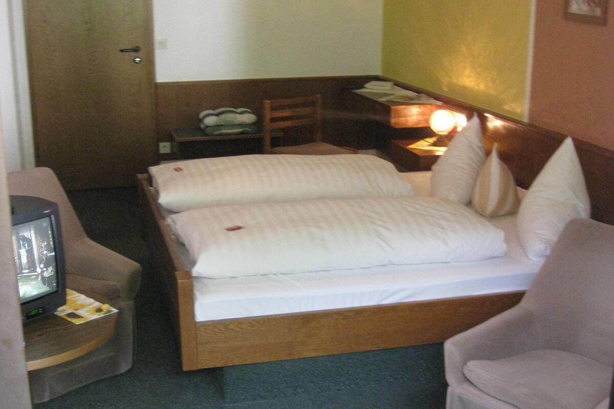 Une chambre d’hôtel avec un lit, une chaise, un bureau et un téléviseur.