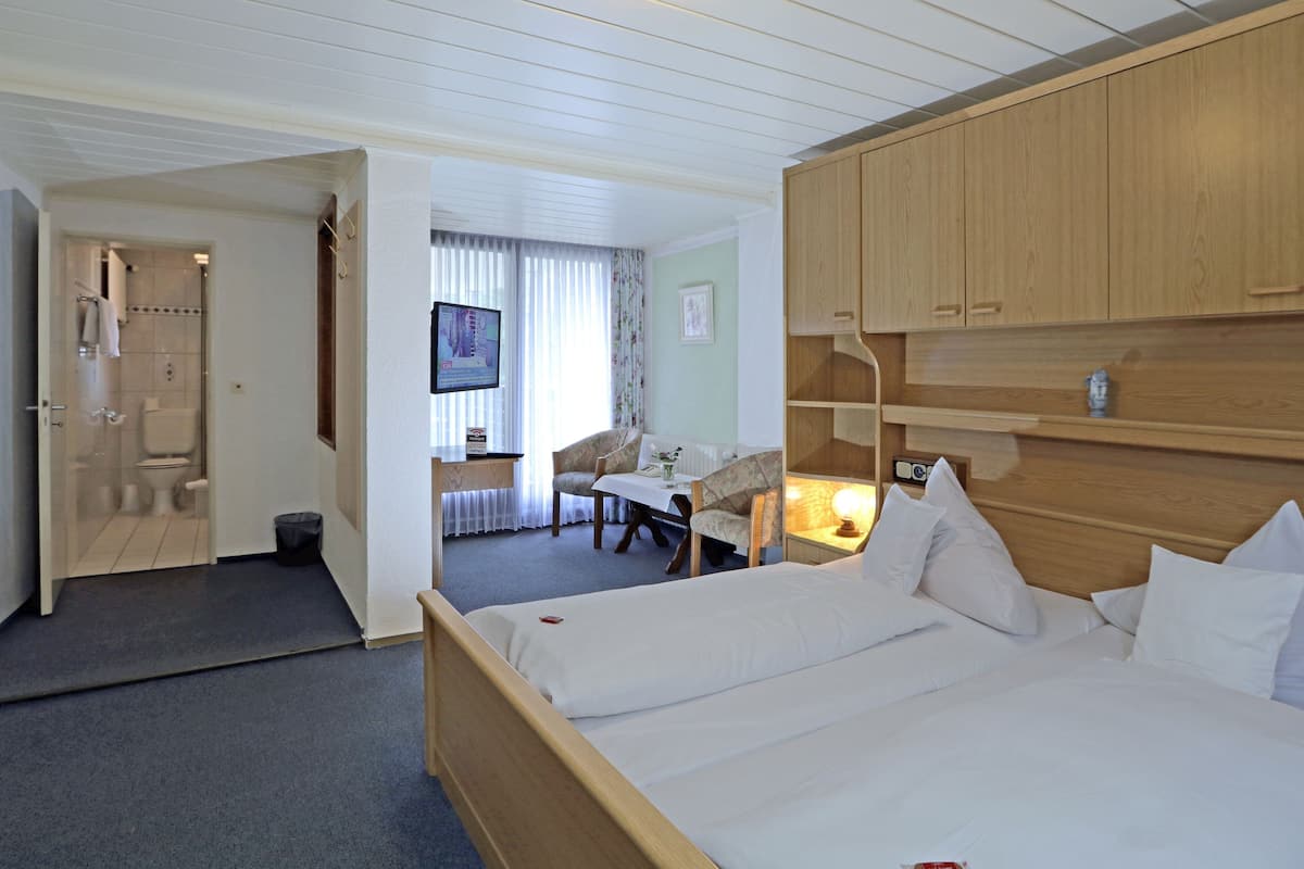 Une chambre d’hôtel équipée d’un lit, d’un bureau, d’une chaise, d’une télévision et d’armoires en bois.