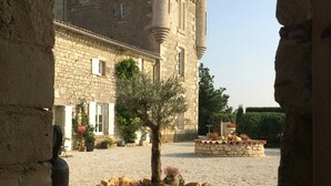 Un patio con un edificio de piedra que tiene ventanas de arco y un árbol en el centro.