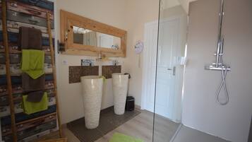 A bathroom with a wooden ladder, two large vases, a mirror, and a shower.