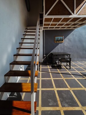 A staircase with wooden steps and white railings, leading to a room with a tiled floor and a table with chairs. - Aether PAI Villa (Pai)
