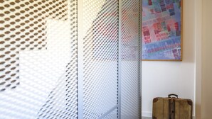 A room with a patterned wall, a suitcase, and a framed artwork. - B&B WarmUp Grosseto (Grosseto)