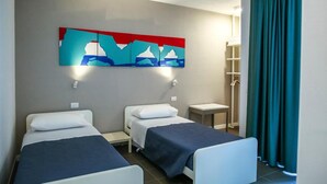 A hotel room with two single beds, a small table, a nightstand, a wall-mounted artwork, and a window with curtains. - B&B WarmUp Grosseto (Grosseto)
