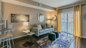 A modern living room with a grey sofa, a round mirror, a coffee table, and a patterned rug.