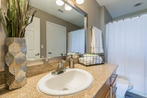 A bathroom with a granite countertop, a white sink, a mirror, a towel rack, and a shower curtain.