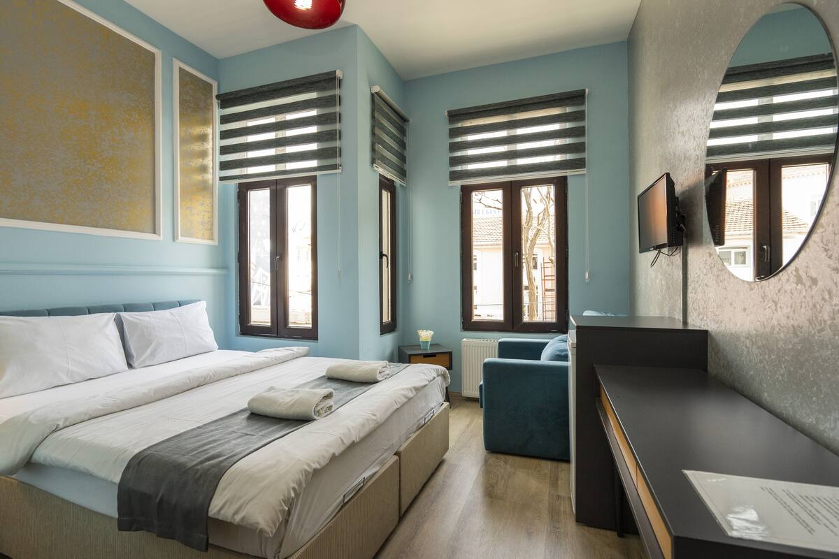 A bedroom with a bed, a desk, a chair, and a TV.